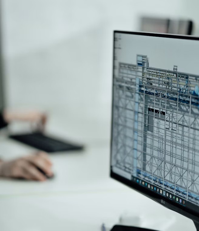 Close-up of architectural blueprints and a laptop displaying CAD software on a clean desk.