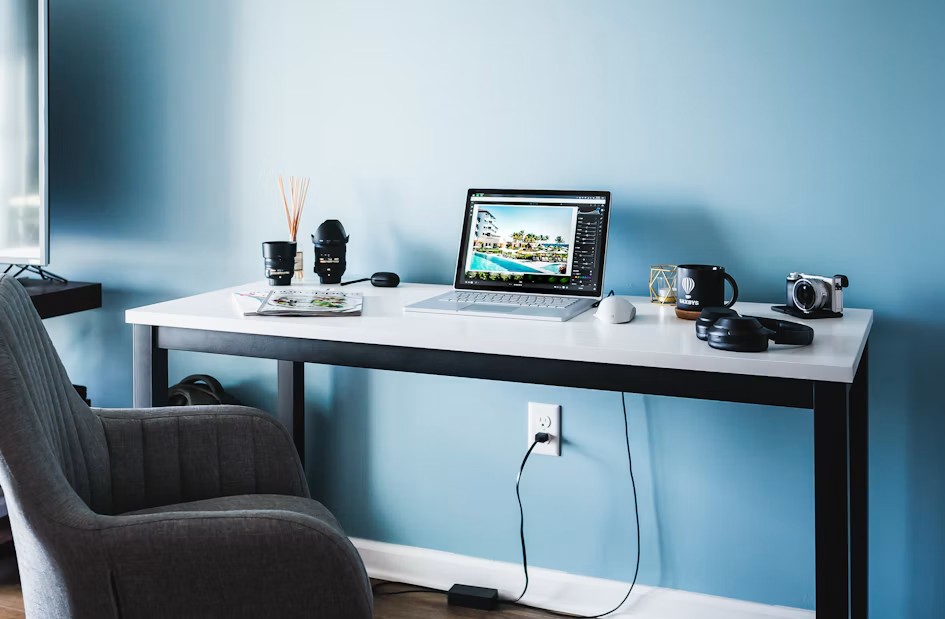 A clean, minimal desk setup with architectural blueprints and a laptop.